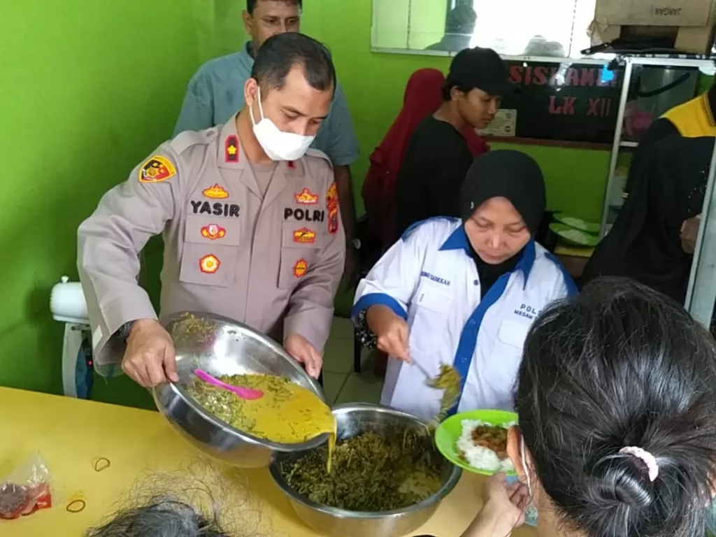 Kapolsek Sunggal Kompol Yasir Ahmadi SH MH, Sik membantu Ibu Ani yang bertugas untuk membagikan makanan di Warung Makan Gratis Polsek Sunggl, Jumat (3/7). (Dok. Humas Polsek Sunggal)