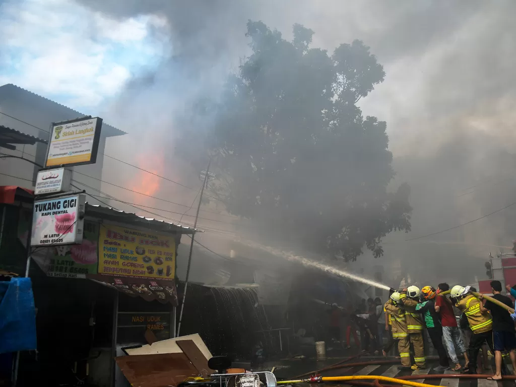 Petugas pemadam kebakaran bersama warga berusaha memadamkan api yang membakar sejumlah toko di Jalan Minangkabau Barat, Manggarai, Jakarta, Selasa (7/7/2020). (ANTARA FOTO/Galih Pradipta)
