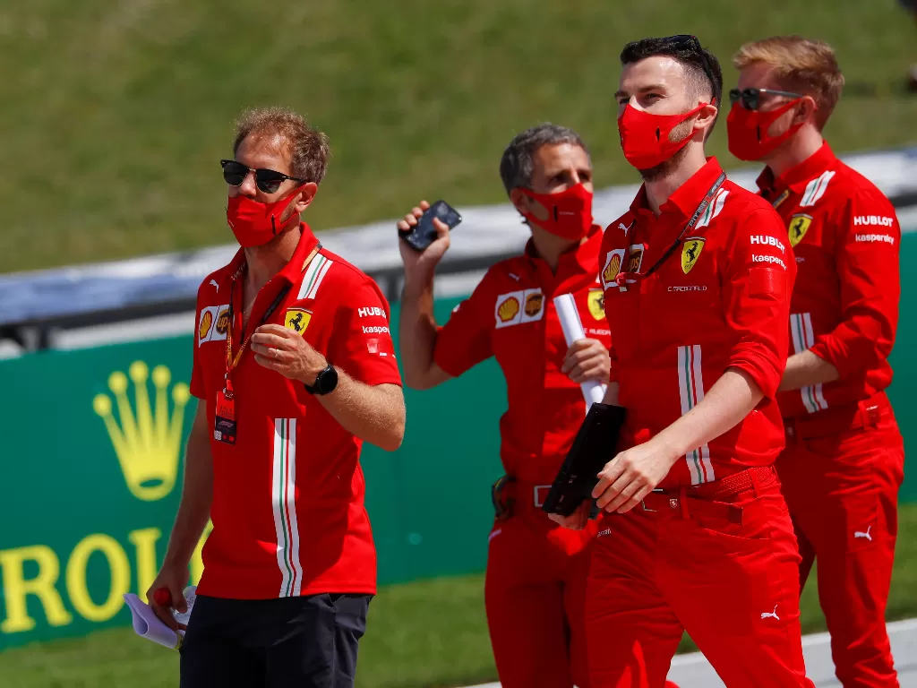 Pembalap senior Ferrrari, Sebastian Vettel dengan anggota kru Ferrari. (REUTERS/LEONHARD FOEGER)