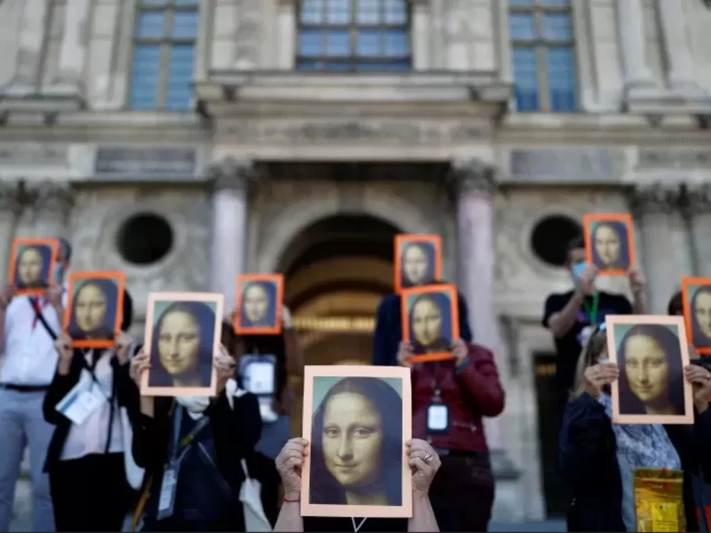 Para pemandu wisata unjuk rasa memegang lukisan Mona Lisa di depan Museum Louvre, Paris.(ANTARA/Reuters/Christian Hartmann)