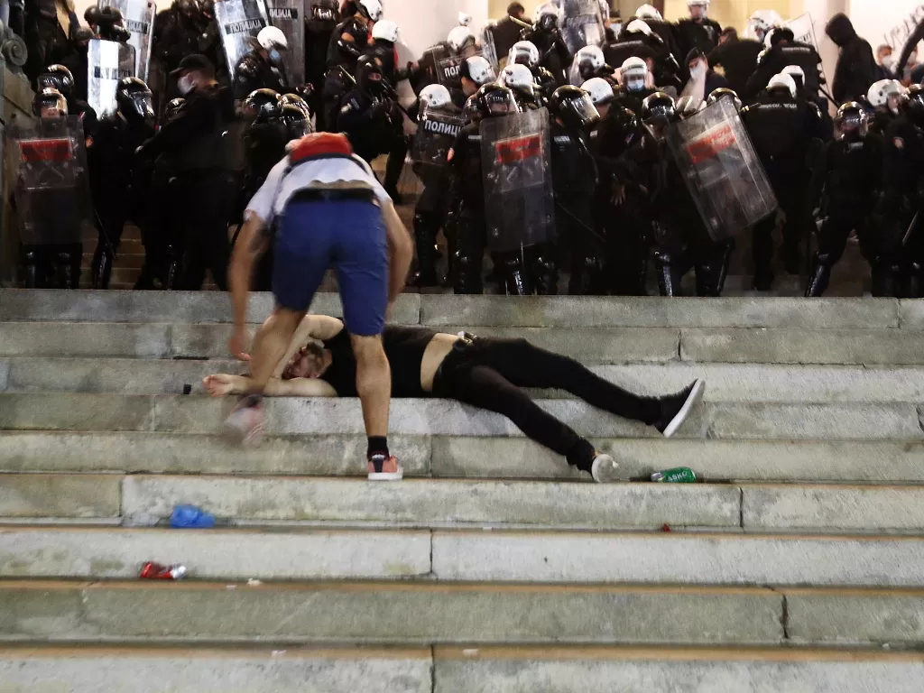 Seorang demonstran yang terluka menerima bantuan ketika dia terbaring di tangga gedung parlemen Serbia saat terjadi aksi protes menentang rencana pemberlakuan 