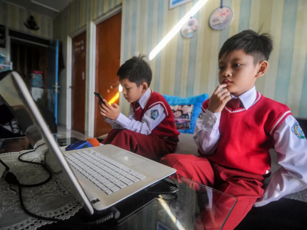 Sepasang anak kembar murid SD Bakti Nusantara mengerjakan Ujian Akhir Semester (UAS) Genap secara daring di kediamannya di Cinunuk, Kabupaten Bandung, Jawa Barat. (ANTARA FOTO/Raisan Al Farisi)