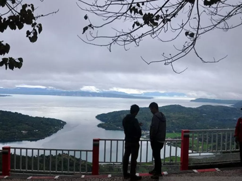 Sejumlah wisatawan menikmati panorama Danau Toba dari atas bukit Taman Sipinsur Dolok Sanggul, Kabupaten Humbang Hasundutan, Sumatera Utara, Sabtu (2/12). (Photo/ANTARA FOTO/Septianda Perdana)