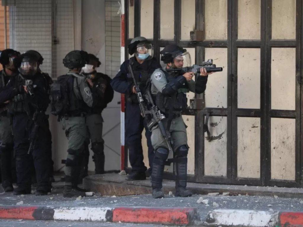 Seorang tentara Israel membidikkan senjatanya ke arah demonstran Palestina saat terjadi bentrokan usai aksi demonstrasi menolak rencana aneksasi Israel di Kota Hebron, Tepi Barat, Jumat (3/7/2020). (ANTARA/Xinhua-Mamoun Wazwaz)