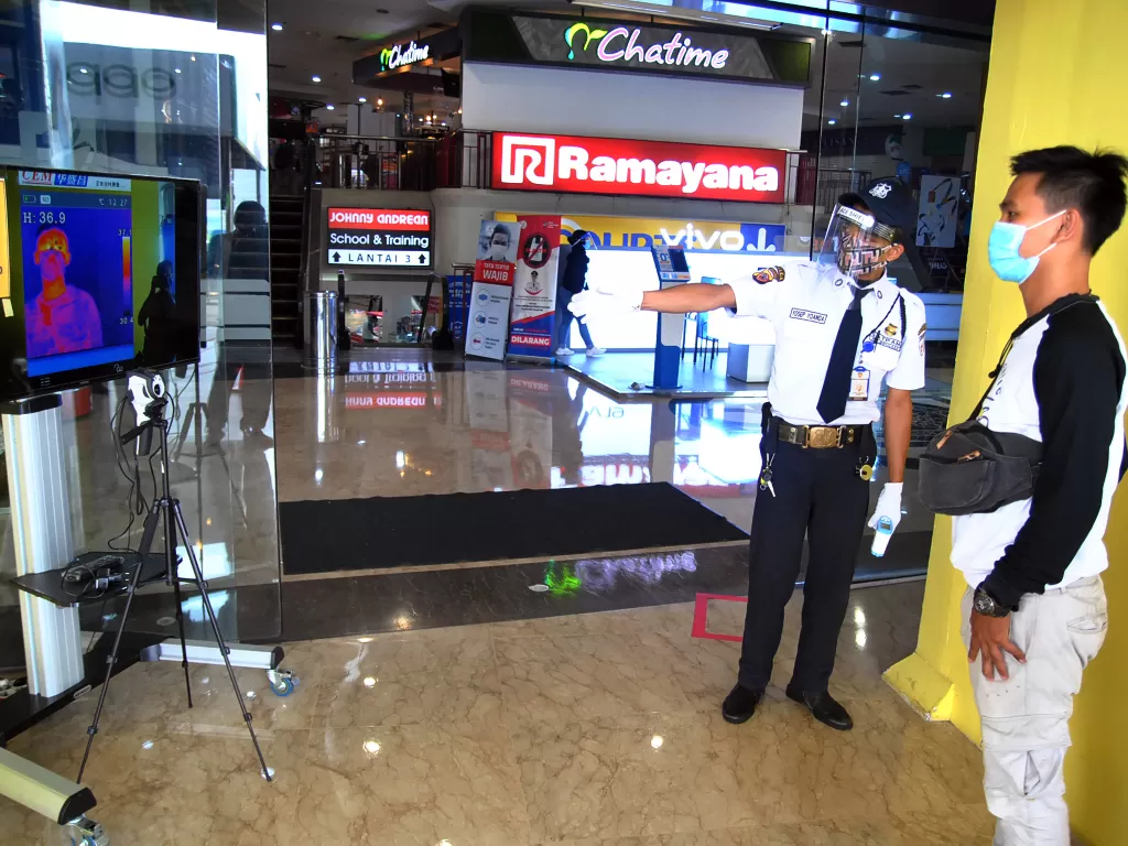 Petugas keamanan memeriksa suhu tubuh pengunjung melalui layar saat pembukaan kembali pusat perbelanjaan Mall BTM, Kota Bogor (ANTARA FOTO/Arif Firmansyah)