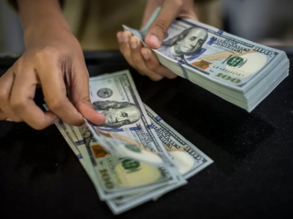 Petugas menghitung pecahan uang dolar AS. (ANTARA FOTO/Aprillio Akbar)