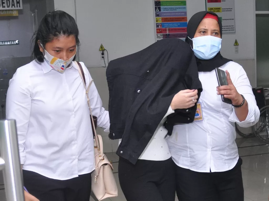 Personel kepolisian membawa artis berinisial H (tengah) saat menjalani pemeriksaan kesehatan di Rumah Sakit Bhayangkara Polda Sumut, Medan, Sumatera Utara, Senin (13/7/2020). (Photo/ANTARA FOTO/Septianda Perdana)
