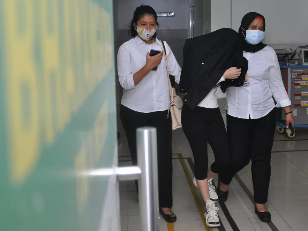 Personel kepolisian membawa artis berinisial H (tengah) saat menjalani pemeriksaan kesehatan di RS Bhayangkara Polda Sumut, Senin (13/7/2020). (ANTARA/Septianda Perdana)