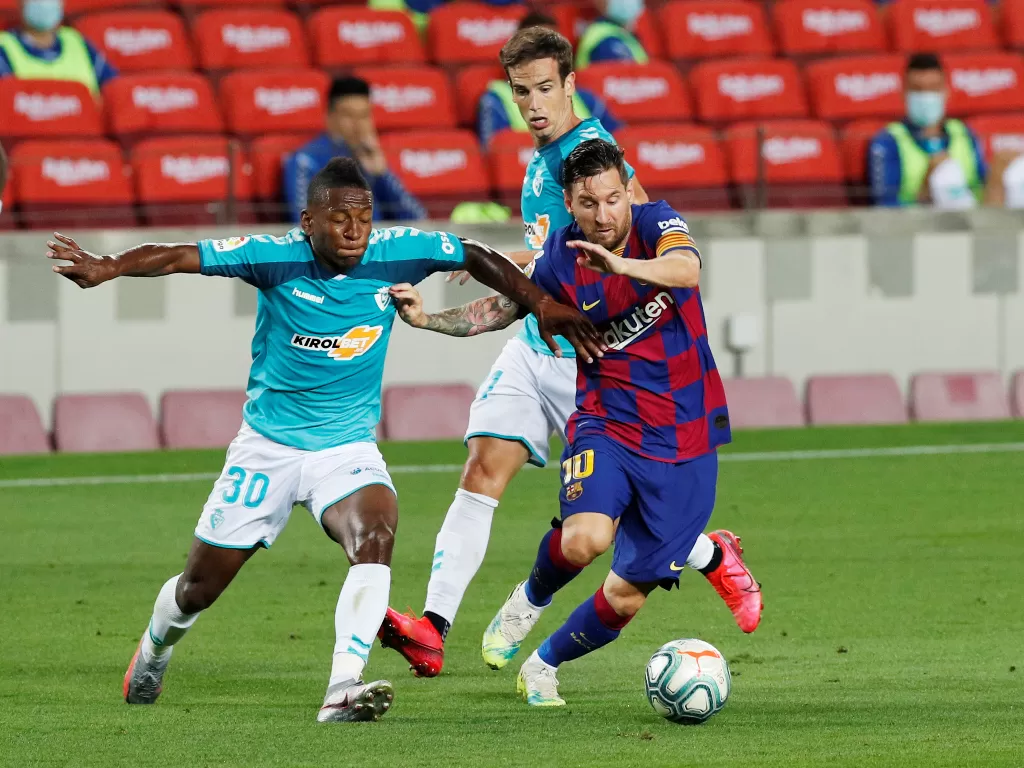 Penyerang Barcelona, Lionel Messi berduel dengan pemain Osasuna, Pervis Estupinan. (REUTERS/Albert Gea)
