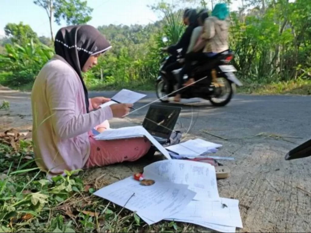 Teara Noviani (kiri) mengerjakan Ujian Tengah Semester secara daring di pinggir jalan kawasan pegunungan Menoreh di Desa Kenalan, Borobudur, Magelang. (ANTARA FOTO/Anis Efizudin/tom)