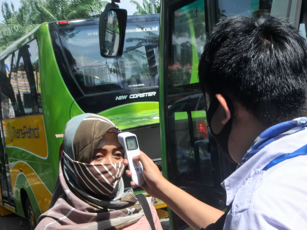 Petugas mengecek suhu tubuh penumpang sebelum menaiki bus Transpatriot di Harapan Indah, Bekasi. (ANTARA/Fakhri Hermansyah)