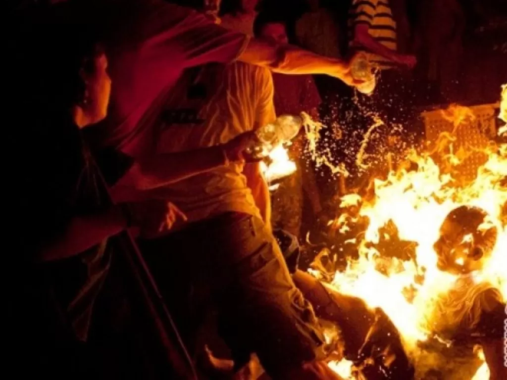 Ilustrasi: warga mencoba memadamkan api pada tubuh seorang yang membakar diri. (REUTERS/Ben Kelmer)