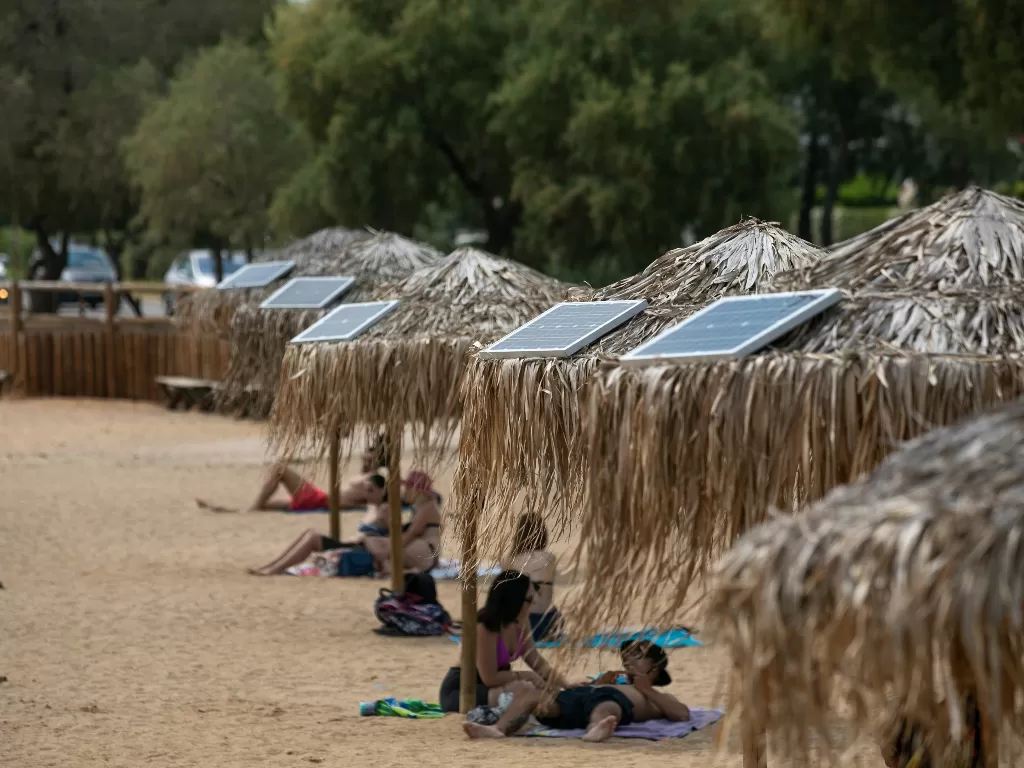 Panel tenaga surya terpasang di sejumlah payung yang ada di pantai terbuka umum di dekat Balai Kota Vari-Voula-Vouliagmeni, sebelah selatan Athena, Yunani, 21 Juli 2020. (Xinhua/Lefteris Partsalis)