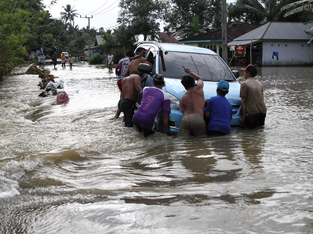 Warga membantu menyelamatkan kendaraan yang terperosok di jalan rusak akibat banjir di Desa Laosu, Konawe, Sulawesi Tenggara, Rabu (22/7/2020). (ANTARA FOTO/Jojon)
