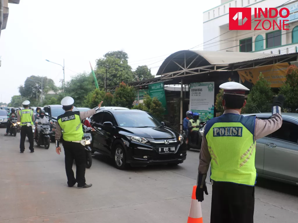  Petugas kepolisian memeriksa kendaraan yang melintas di cek poin Lampiri, Kalimalang, Jakarta, Jumat (22/5/2020). (INDOZONE/Febio Hernanto) 