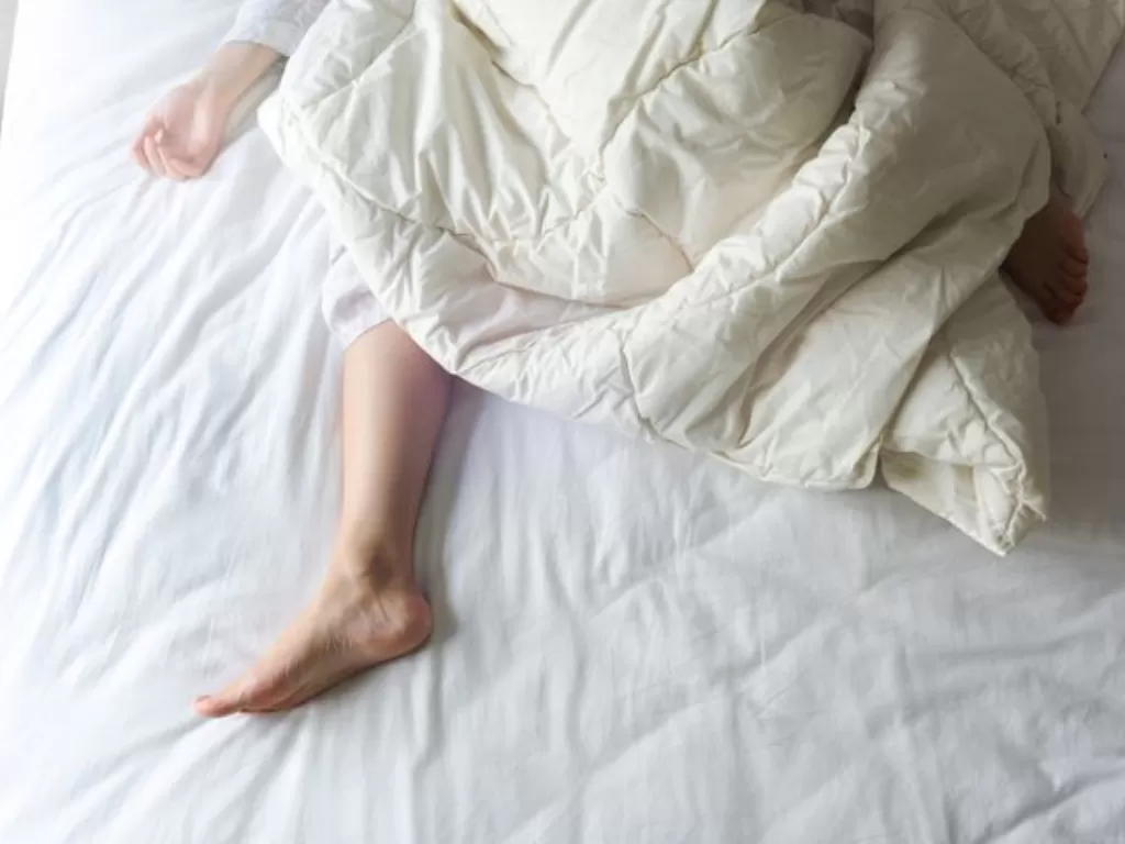 Ilustrasi tidur dengan mengeluarkan satu kaki dari selimut. (Huffingtonpost)