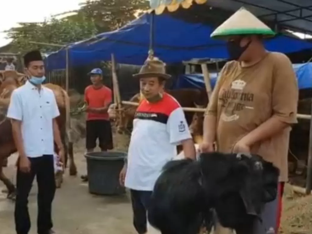 Pedagang hewan kurban, Adin (kedua dari kanan) menyerahkan satu ekor kambing jenis etawa kepada konsumen di Jalan Kincan, Pondok Kelapa, Duren Sawit, Jakarta Timur. (ANTARA/Andi Firdaus).