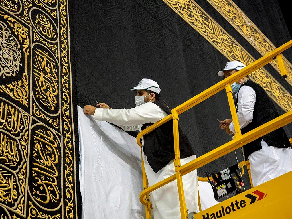Pekerja yang mengenakan topeng pelindung bekerja untuk membangkitkan Kiswa, kain sutra yang menutupi Ka'bah. (Photo/REUTERS/Saudi Press Agency)