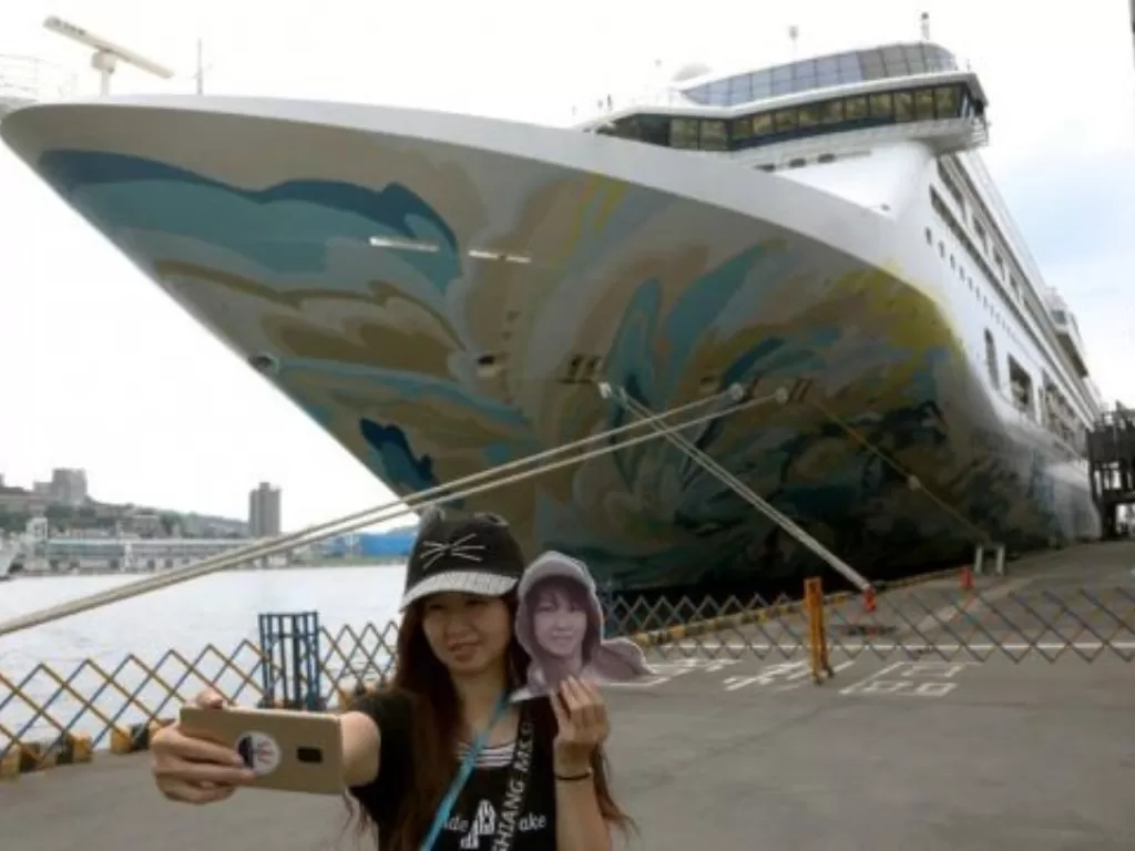 Seorang wanita sedang selfie di depan kapal pesiar, Taiwan. (REUTERS)
