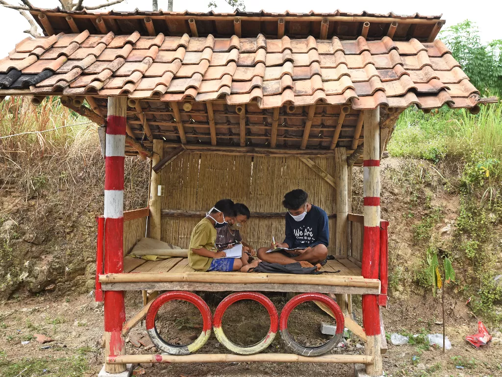 Sejumlah murid SD Negeri Jakung mengikuti proses belajar mengajar dalam jaringan (daring) di pos ronda di tepi jalan supaya bisa mendapat sinyal di Kampung Gunungsari, Serang, Banten, Rabu (29/7/2020). (Photo/ANTARA FOTO/Asep Fathulrahman)