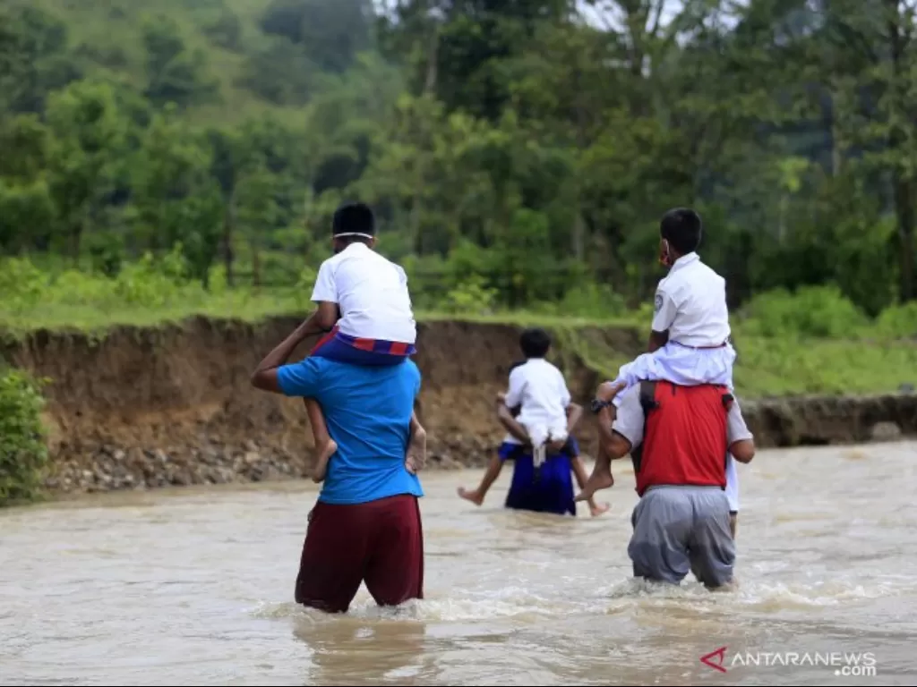 Sejumlah siswa dan guru Sekolah Dasar Negeri (SDN) 6 Tapa dibantu warga melintasi sungai Polanggua. (ANTARA FOTO/Adiwinata Solihin)