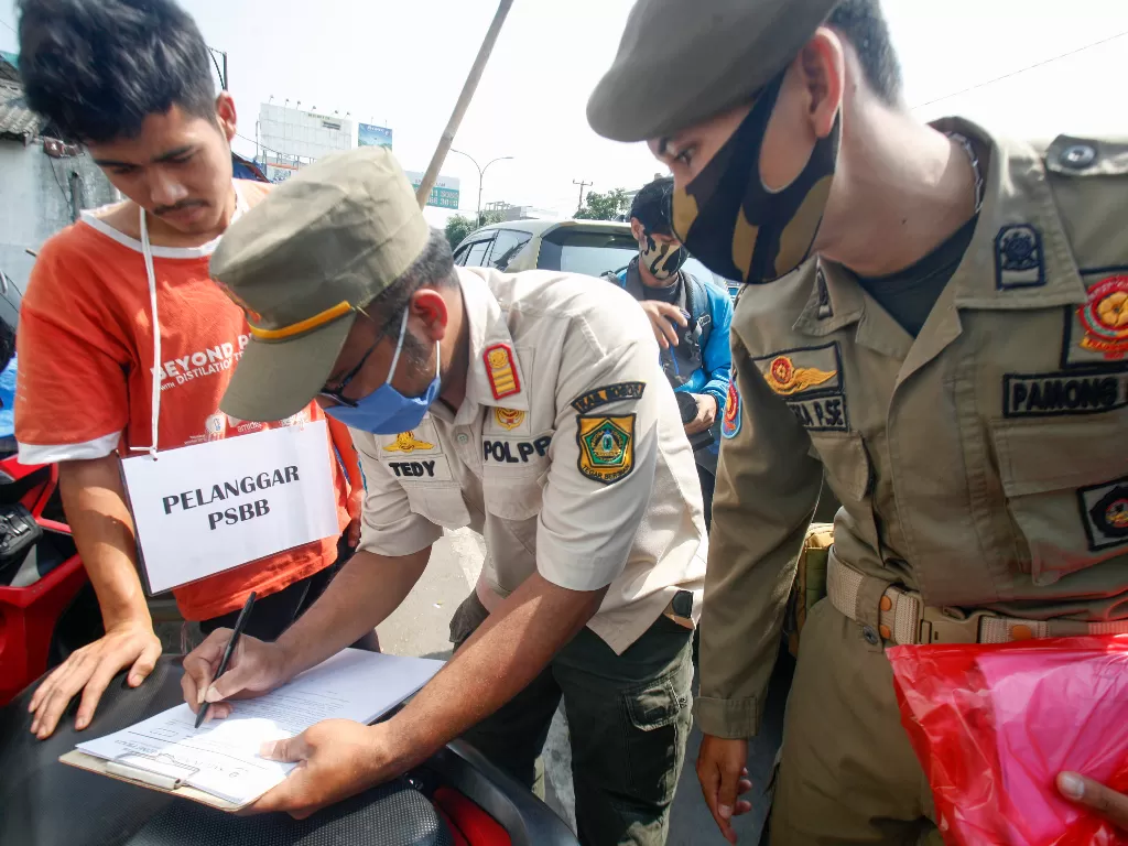 Petugas Satpol PP menilang warga yang tidak menggunakan masker di kawasan Pasar Cibinong, Kabupaten Bogor, Jawa Barat, Rabu (29/7/2020). (Photo/ANTARA FOTO/Yulius Satria Wijaya)