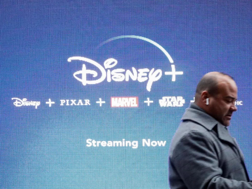 Foto seorang pria sedang berada di depan logo layanan streaming Disney+ (photo/REUTERS/Brendan Mcdermid)