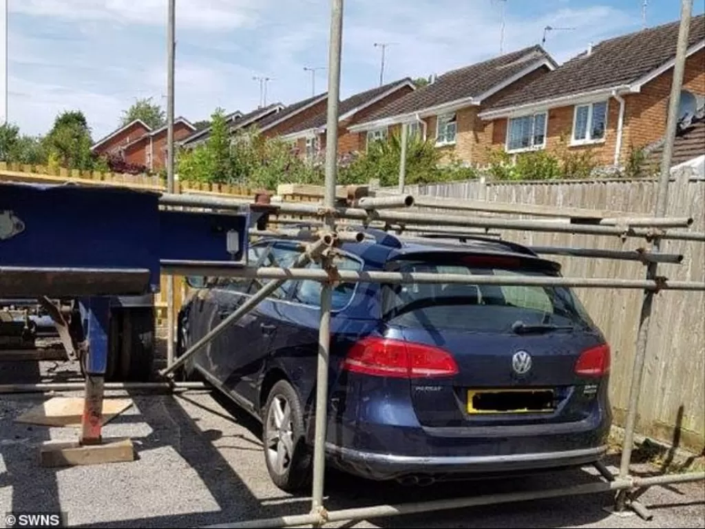Tampilan Volkswagen Passat yang dikurungi pipa besi akibat masalah tempat parkir. (dailymail.co.uk)