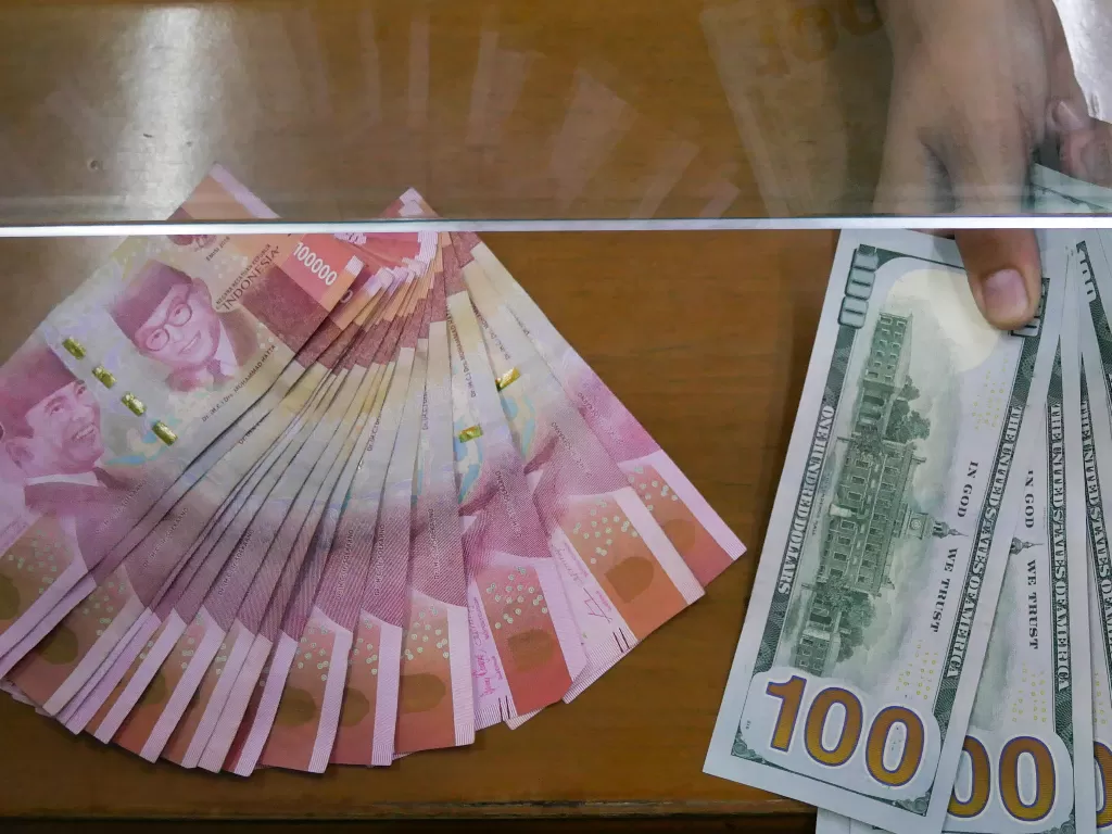Petugas menunjukkan uang pecahan rupiah dan dolar AS (USD) di tempat penukaran uang Dolarindo, Melawai, Jakarta, Rabu (22/7/2020). (ANTARA FOTO/Rivan Awal Lingga)