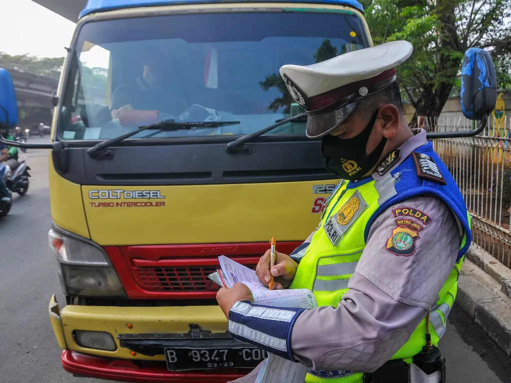 Polantas memberikan sanksi tilang kepada pengendara truk yang melanggar aturan ganjil genap di Simpang Cawang, Jakarta Timur, Senin (10/8/2020). (ANTARA FOTO/Fakhri Hermansyah)