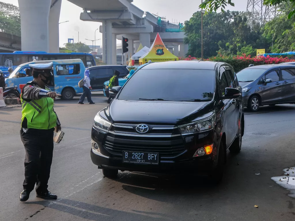 Polantas memberhentikan mobil yang melanggar aturan ganjil genap di Simpang Cawang, Jakarta Timur, Senin (10/8/2020). (ANTARA FOTO/Fakhry Hermansyah)