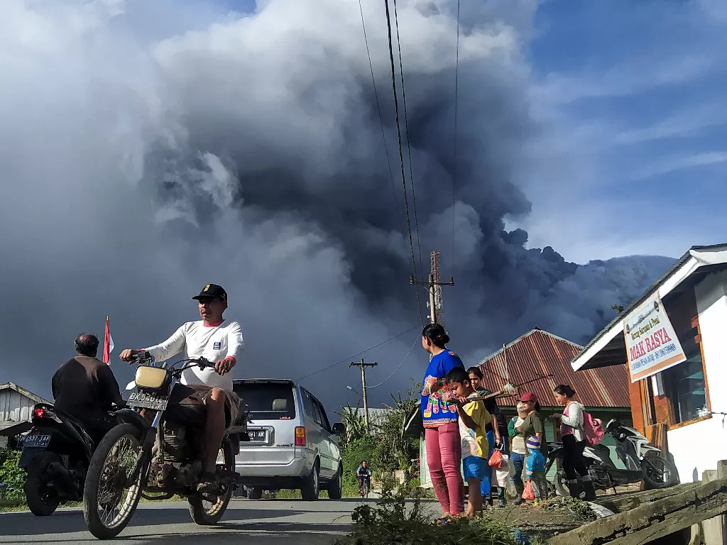 Sejumlah pengendara melintas di Jalan Karo-Langkat dengan latar belakang Gunung Sinabung yang menyemburkan material vulkanik di Desa Kutarayat, Naman Teran, Karo, Sumatera Utara, Kamis (13/8/2020). ANTARA FOTO/Sastrawan Ginting