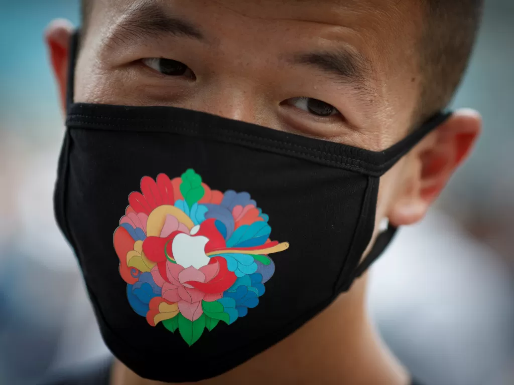 Seorang pria di Tiongkok sedang menggunakan masker berlogo Apple (photo/REUTERS/Thomas Peter)