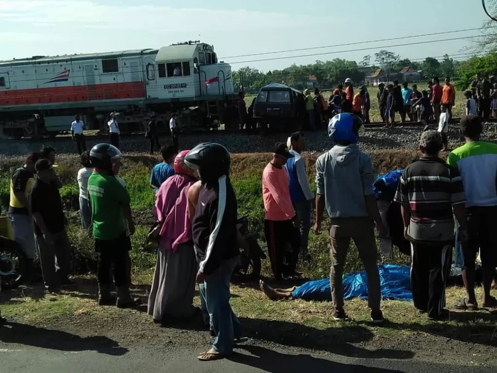 Warga berkumpul menyaksikan mobil keluarga yang ditabrak kereta api di Desa Ngebrak, Kecamatan Gampengrejo, Kediri, Senin (17/8/2020).
