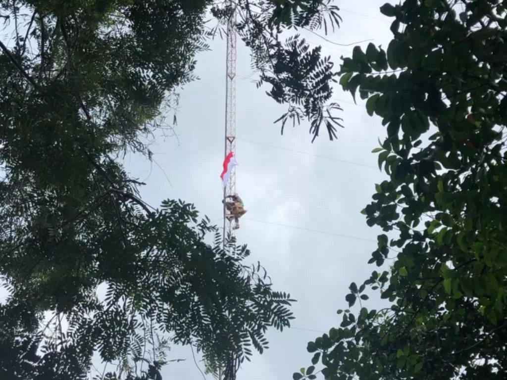 Warga Pulau Belakangpadang mengibarkan bendera dengan memanjat menara radio, Senin (17/8/2020). (Dok. Camat Belakangpadang)