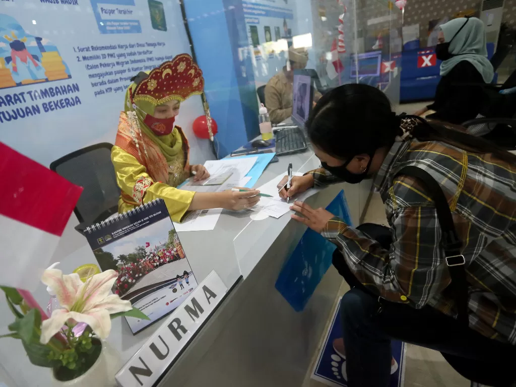 etugas berpakaian adat nusantara melayani pemohon paspor di Kantor Imigrasi Kelas II Non TPI Blitar, Jawa Timur, Jumat (14/8/2020). (ANTARA FOTO/Irfan Anshori)
