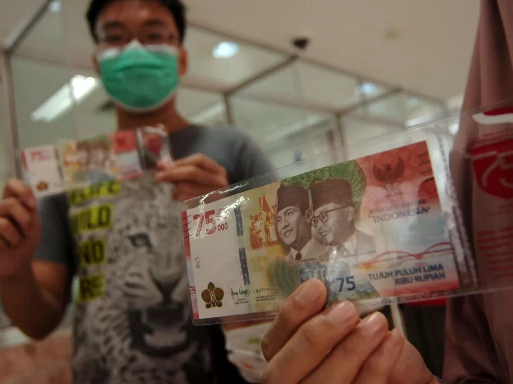 Sejumlah warga menunjukkan uang baru pecahan Rp75.000 saat penukaran Uang Peringatan Kemerdekaan 75 Tahun Republik Indonesia di Kantor Perwakilan (Kpw) Bank Indonesia (BI), Tegal, Jawa Tengah, Selasa (18/8/2020). (ANTARA FOTO/Oky Lukmansyah)