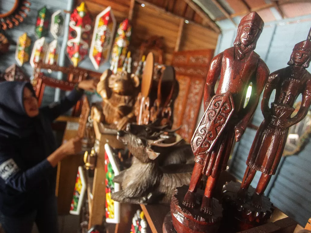 Penjual kerajinan ukiran kayu motif Dayak Kalimantan Tengah membersihkan produknya di kiosnya di Jalan RTA Milono, Palangkaraya, Kalimantan Tengah, Kamis (13/8/2020). (ANTARA FOTO/Makna Zaezar)