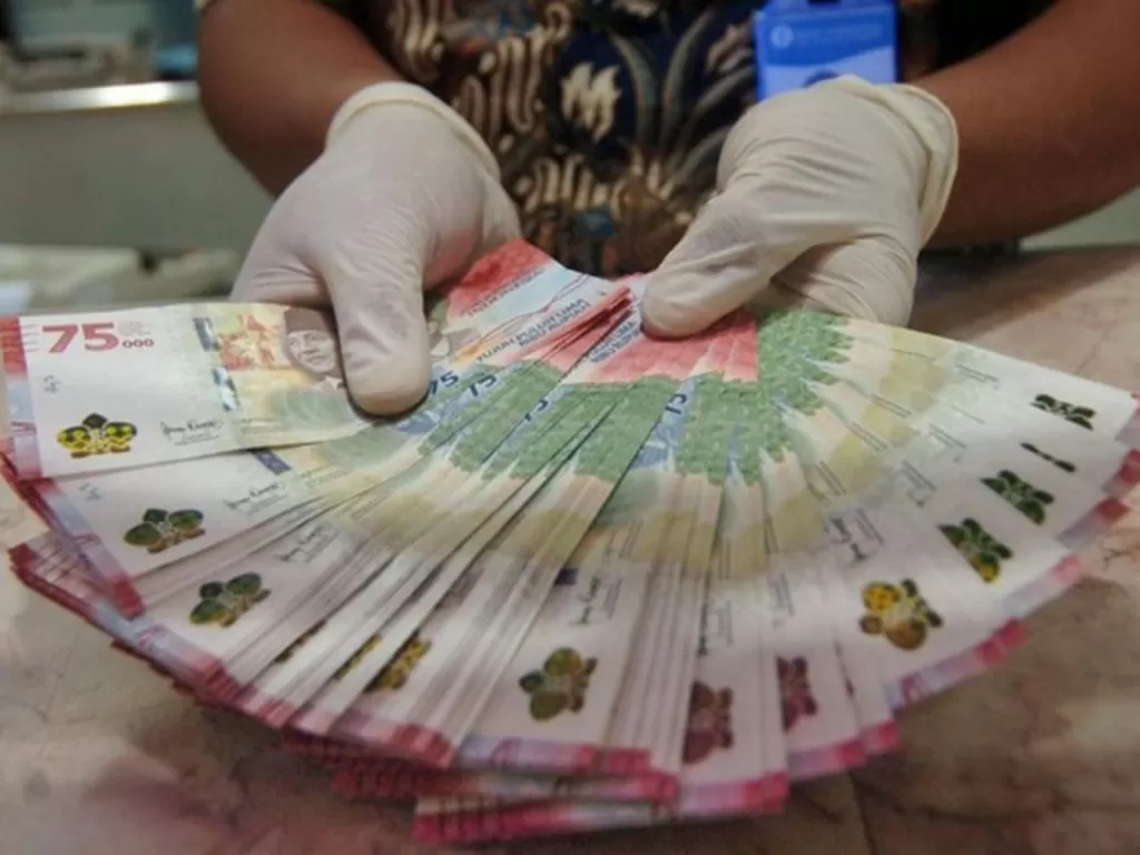 Petugas menunjukkan uang baru pecahan Rp75 ribu. (ANTARA FOTO/Oky Lukmansyah)