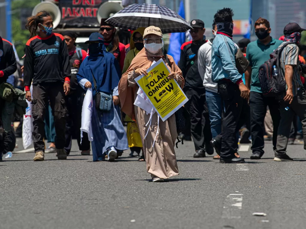 Seorang buruh membawa poster protes dalam aksi unjuk rasa di depan kompleks Parlemen, Senayan, Jakarta, Selasa (25/8/2020). ANTARA FOTO/Aditya Pradana Putra