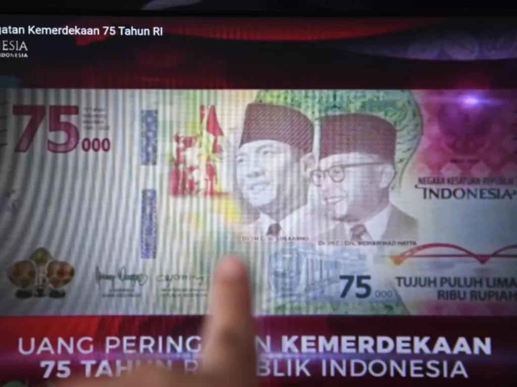 Warga memotret layar yang menampilkan uang lembar pecahan Rp75.000 saat diluncurkan secara virtual (ANTARA FOTO/Hafidz Mubarak A)