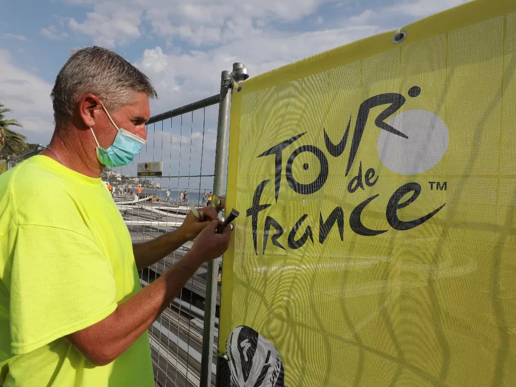 Seorang pria memasang spanduk untuk Grand Depart of the 2020 Tour de France balap sepeda (REUTERS/ERIC GAILLARD)