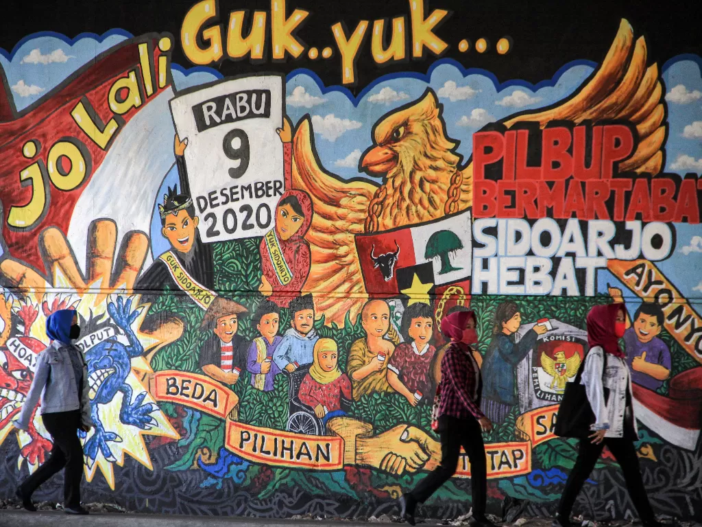 Warga berjalan di depan mural Pemilu 2020 di kawasan Jati Raya, Sidoarjo, Jawa Timur, Jumat (28/8/2020). ANTARA FOTO/Umarul Faruq