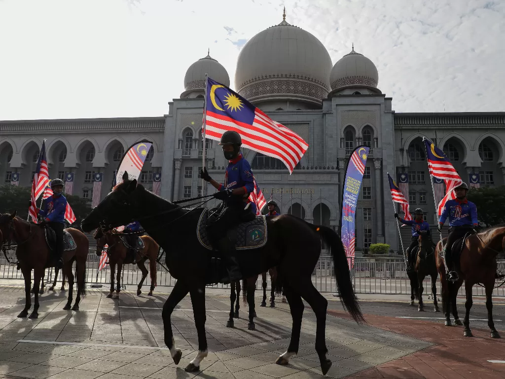 Penunggang kuda yang memegang bendera Malaysia mengikuti gladi bersih acara Hari Kemerdekaan, di Putrajaya, Malaysia (REUTERS/LIM HUEY TENG)