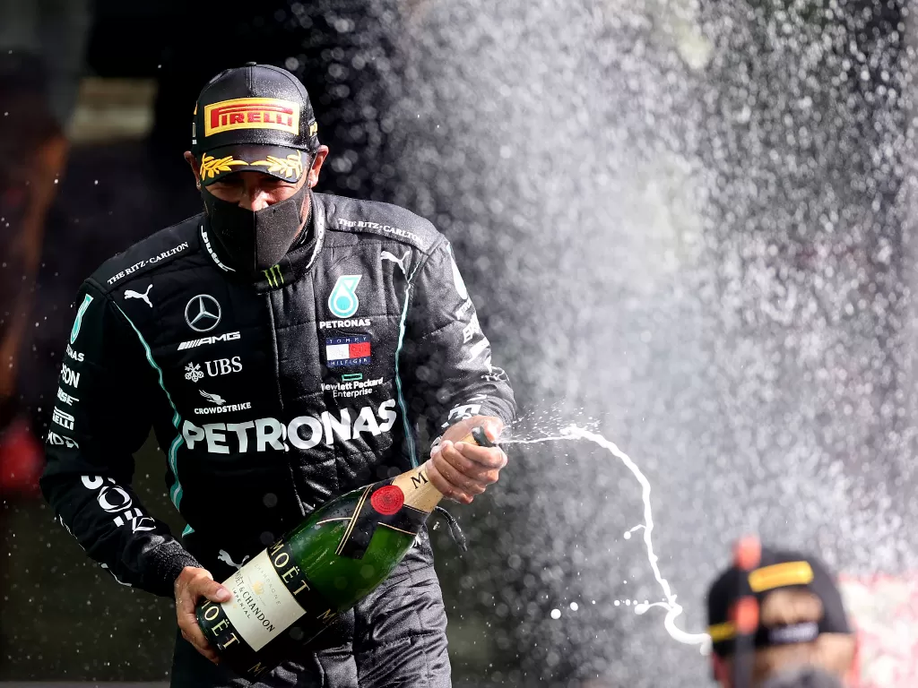 Lewis Hamilton merayakan dengan sampanye di podium setelah memenangkan balapan (REUTERS/LARS BARON)