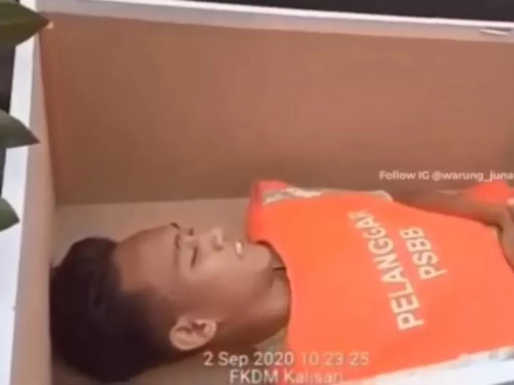Tangkapan layar seorang pemuda dihukum masuk ke peti mati karena tidak pakai masker. (Instagram/@warung_jurnalis)