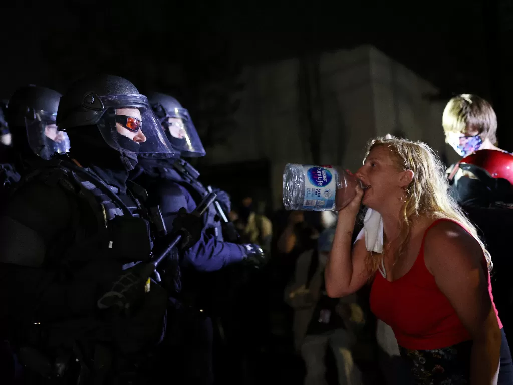 Seorang wanita menghadapi petugas polisi (REUTERS/Carlos Barria)