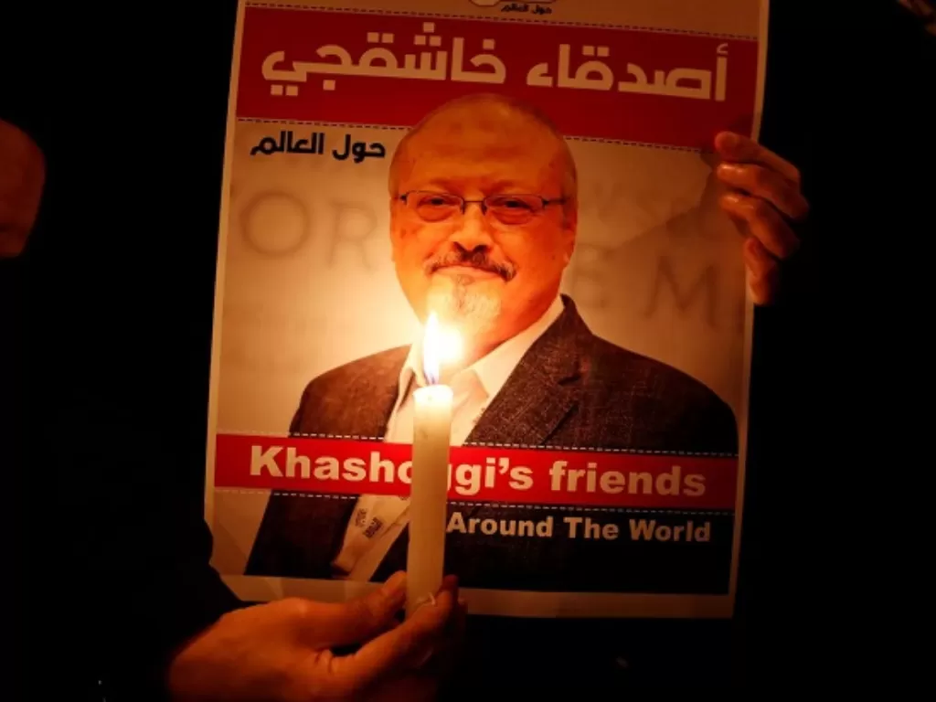 Aktivis menyalakan lilin yang menerangi poster Jamal Khashoggi, jurnalis Arab Saudi yang dibunuh di Istanbul 2 Oktober 2018. (REUTERS)
