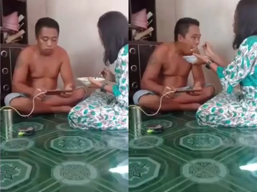 Pria yang makan sambil main game, disuapi oleh sang isri. (photo/Instagram/@makassar_iinfo)