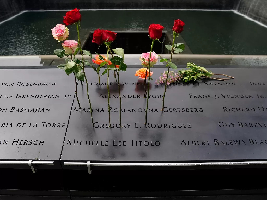 Bunga-bunga ditancapkan di atas kolam yang tertulis nama-nama korban (REUTERS/Carlo Allegri)